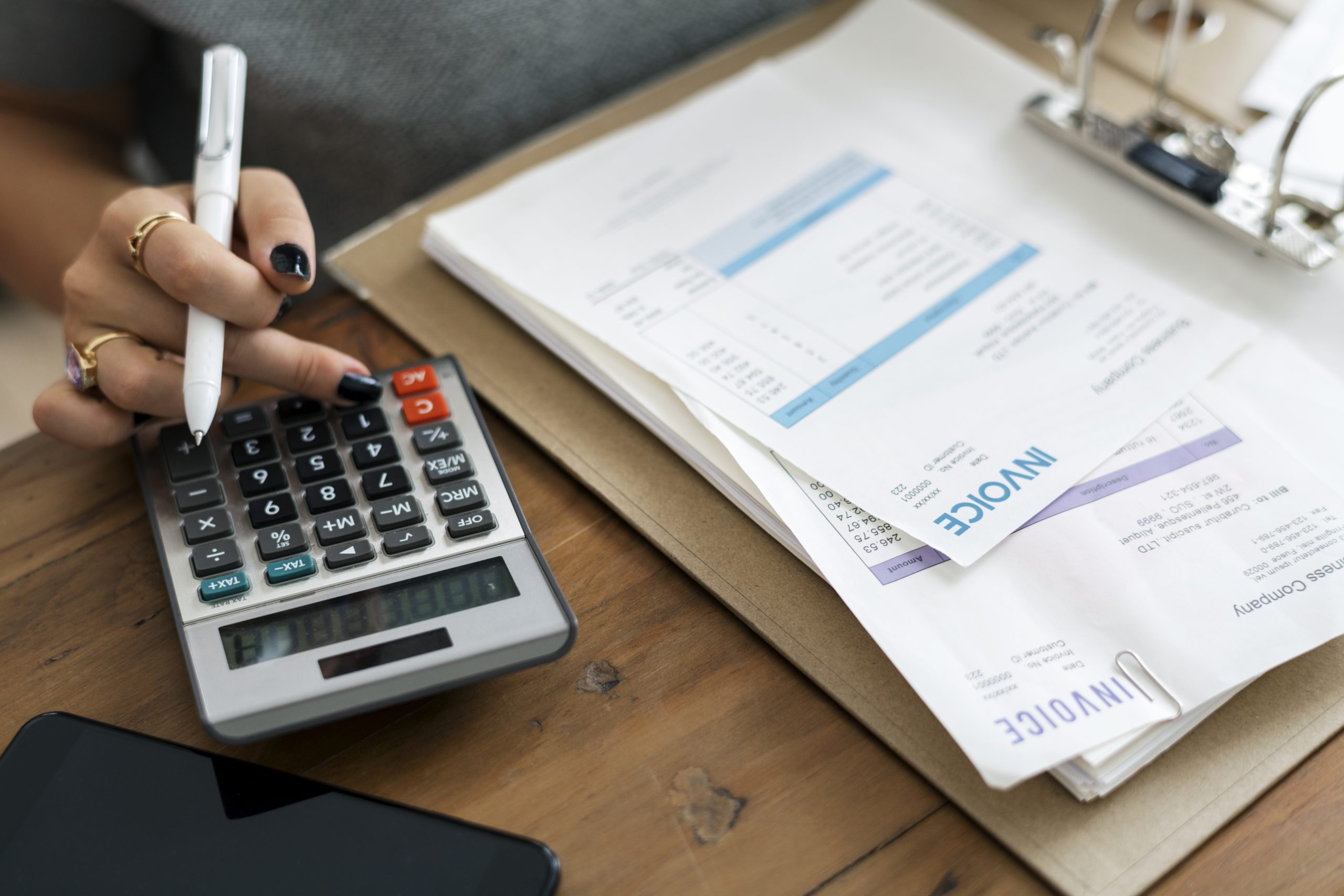 Person calculating multiple bills using a calculator